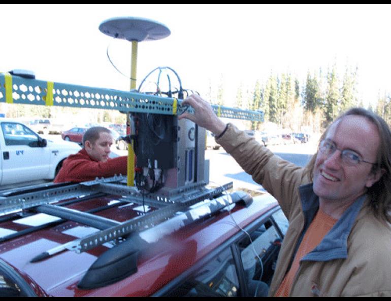 Geophysical Institute graduate student Austin Johnson, left, and glacier researcher Chris Larsen install a GPS laser system on top of Larsen’s Subaru Legacy on the UAF campus. Photo by Ned Rozell