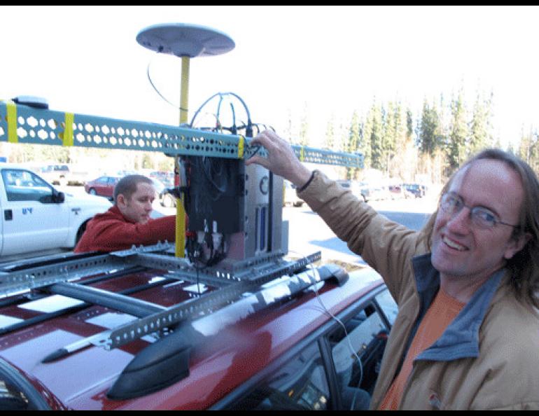  Geophysical Institute graduate student Austin Johnson, left, and glacier researcher Chris Larsen install a GPS laser system on top of Larsen’s Subaru Legacy on the UAF campus. Photo by Ned Rozell