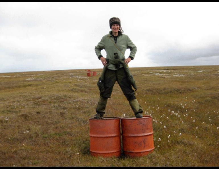  Stacey Fritz standing atop two 55-gallon drums used to mark a runway at a former Dew Line site in Alaska’s Arctic. Photo by Ryan Tinsley. 