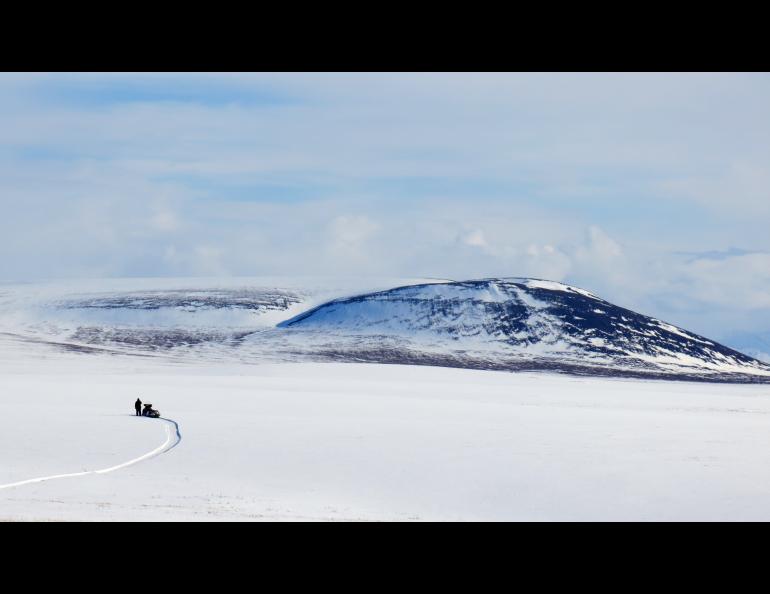 Snow covered field with a hill in the background.