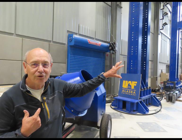 man gesturing inside a garage bay gesturing to large blue beams behind him