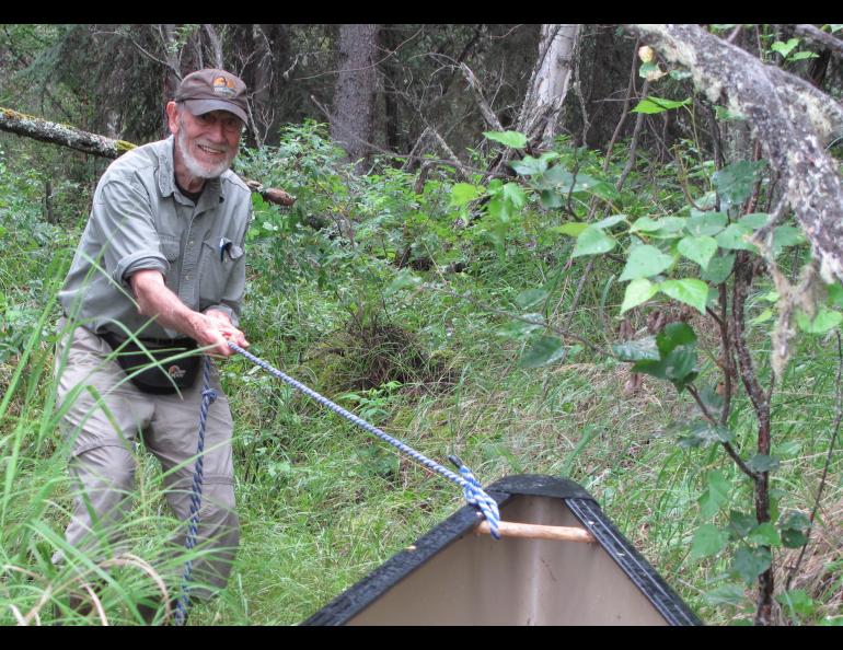 Dave Klein pulls a canoe through the woods to reach a small lake in Alaska’s Interior. Photo by Ned Rozell.
