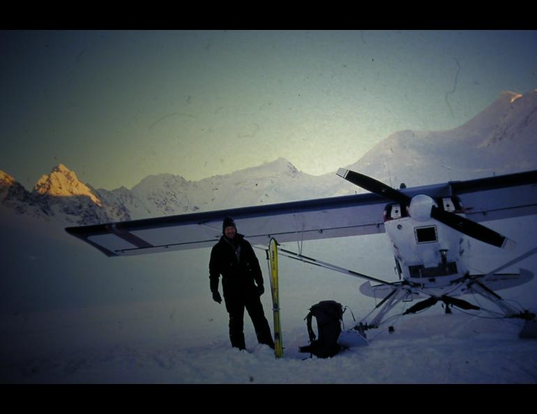 A person standing by a plane on an Alaska glacier