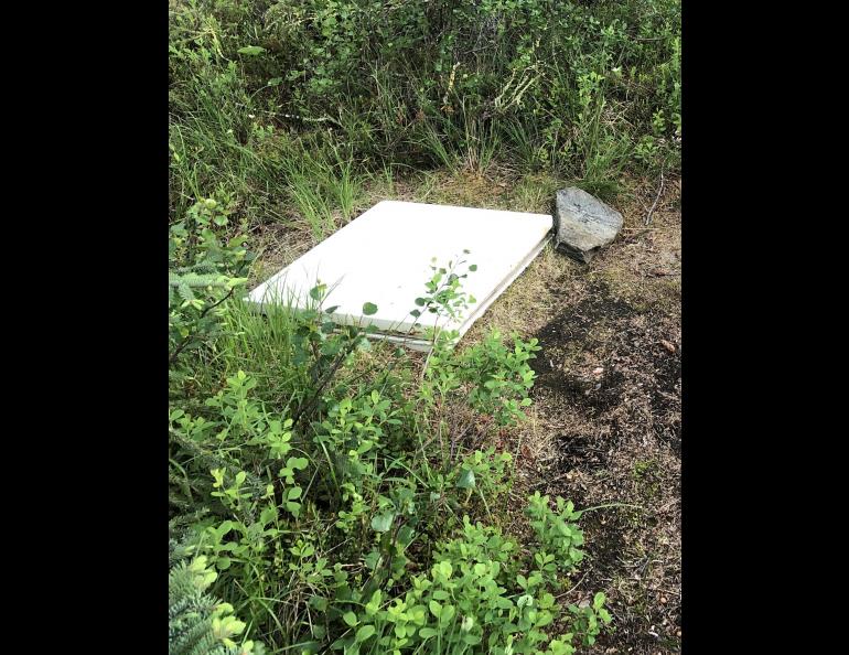 The top of a freezer John Gaedeke sank into permafrost ground at his lodge in the Brooks Range. Warmish permafrost surrounding the freezer keeps the temperature stable enough that beers left inside for the entire frigid winter do not freeze. Photo by Alice Bailey.