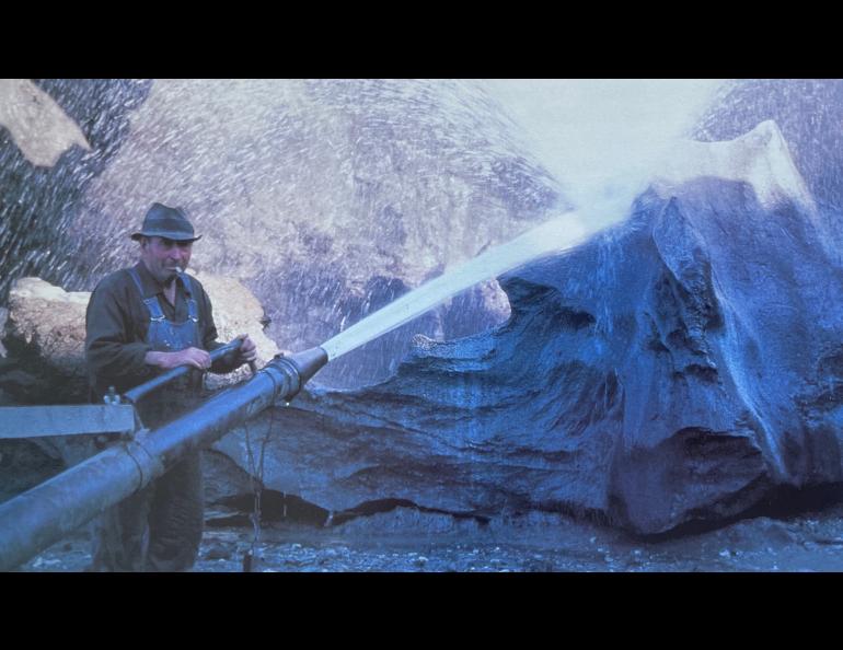 In 1979, gold miner Walter Roman stands with his “monitor” hose used to strip away soil and vegetation. Photo by Dale Guthrie.