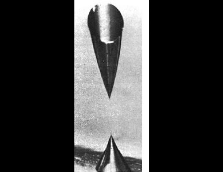 Electron microscope photograph of a track left by a cosmic ray in a thin detector carried aboard Apollo 14. The track shows typically conical shape because acid has etched it more near the entrance and exit points than in the middle.