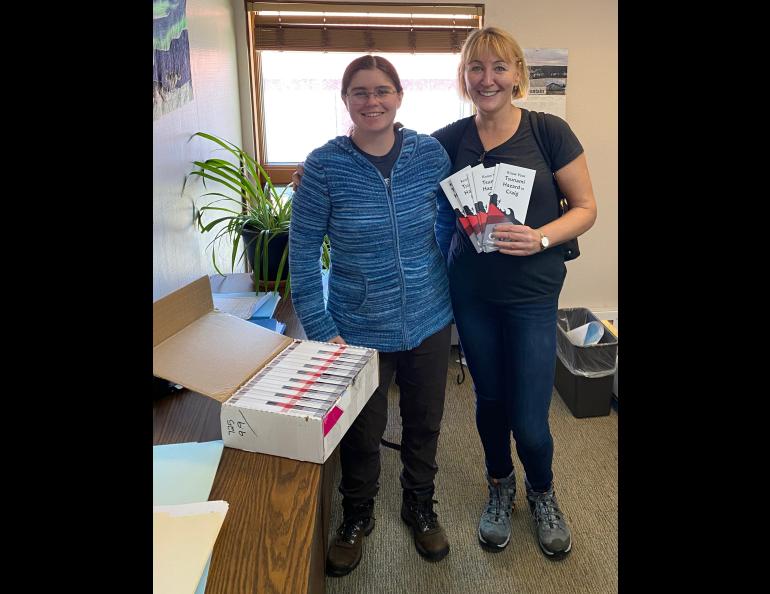 Two people stand in an office hold brochures about tsunami risk