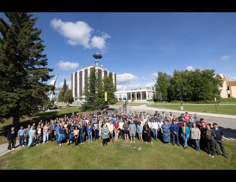 Group of people on a lawn in front of university buildings
