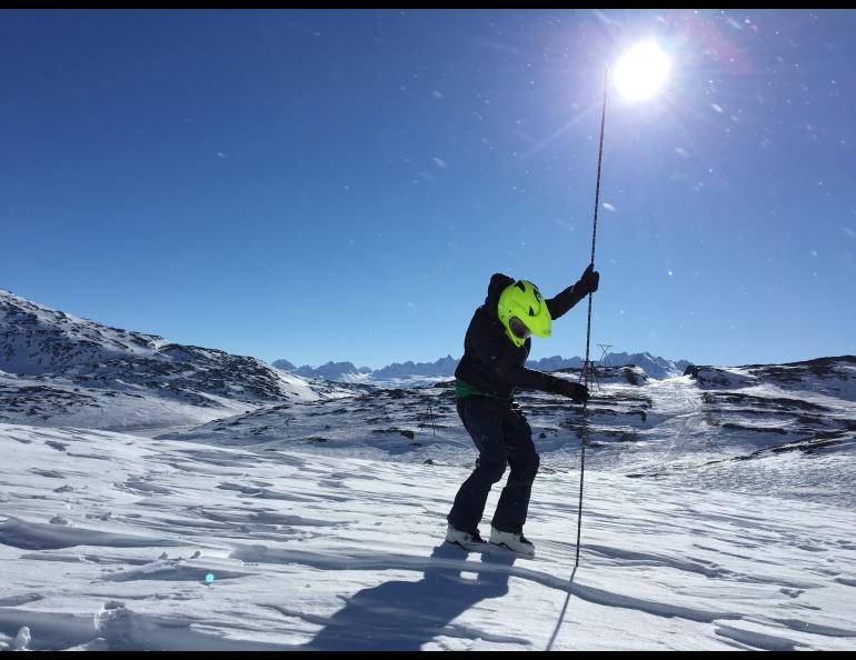 A snowmachiner in Thompson Pass measures snow depth with an avalanche probe. Photo by Gabe Wolken.
