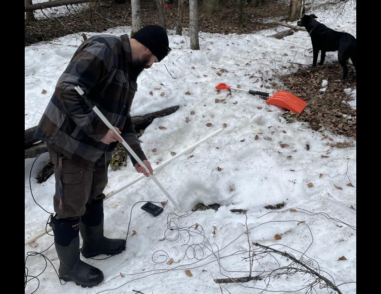 Colby Wright of the University of Alaska Fairbanks Geophysical Institute extends a camera into a sinkhole that developed in the northeast corner of campus. Photo by Ned Rozell.