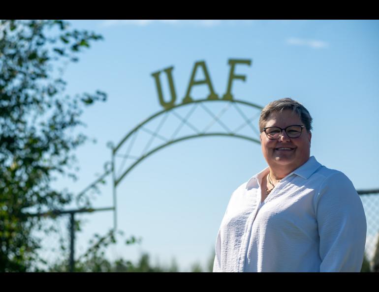 A person in a white shirt stands in front of a gate with “UAF” lettering.