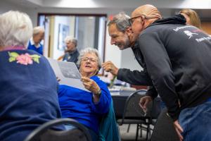 Roberta Greenlee, Kevin Abnett and Mitch Robinson gleefully review a photo at the 2026 GI reunion. Photo by Eric Marshall