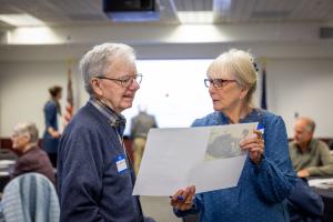 Tom Hallinan (left) and Sue Royston discuss one of the photos Communications staff put out for 2026 GI reunion participants to ID. Photo by Eric Marshall