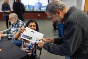 Anupma Prakash shows Kevin Abnett a reprint of a GI publication at the 2026 GI reunion. Photo by Eric Marshall
