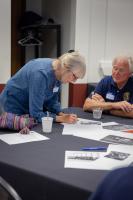 Sue Royston labels a photo while John Dashiell looks on at the 2026 GI reunion. Photo by Eric Marshall