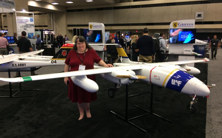 Cathy Cahill, director of the Alaska Center for Unmanned Aircraft Systems Integration, with UAF’s Griffon Aerospace Outlaw SeaHunter UAS at a conference. Photo courtesy Alaska Center for Unmanned Aircraft Systems Integration.