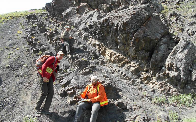 Sedimentary rocks of the Cantwell Formation, representing a prehistoric floodplain environment, are shown in this June 2017 photograph. Dinosaur tracks are visible at the base of the thick, upper sandstone bed. Photo by Paul McCarthy