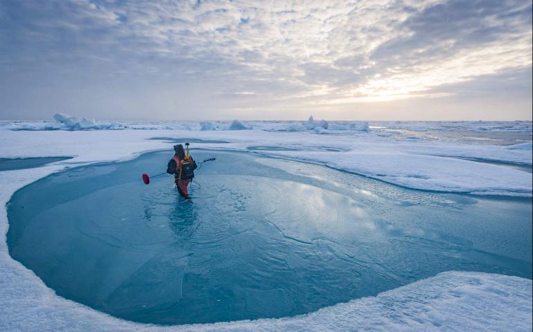 Melinda Webster carries a magnaprobe to measure the depth of melt ponds. Photo by Lianna Nixon