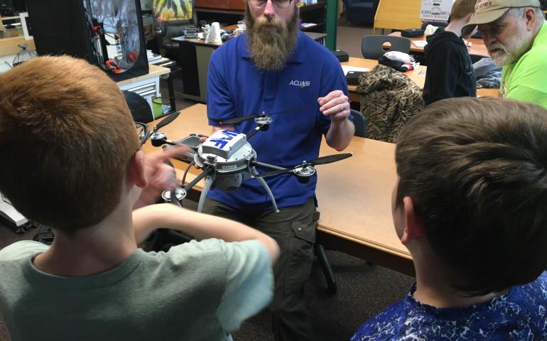 Nick Adkins explains the parts of a drone and its flight capabilities to Delta Junction students. School librarian Norm Cosgrove, who teaches the weeklong summer school drones class, listens. Photo by Rod Boyce