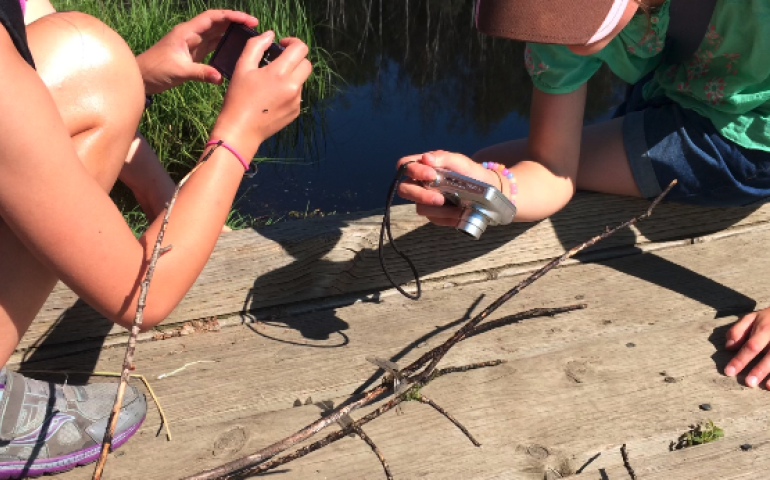 Girls take photos of a dragonfly at Creamer’s Field Migratory Waterfowl Refuge during summer camp. Photo by Perrin Teal Sullivan