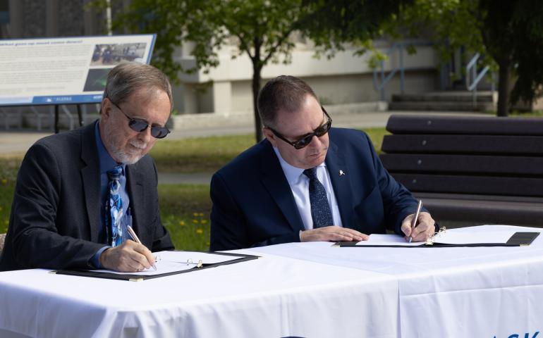 UAF Geophysical Institute Director Bob McCoy and Alaska Aerospace Corp. CEO John Oberst sign a memorandum of understanding in front of the GI building on Thursday, June 10, 2025. UAF/GI photo by Bryan Whitten: