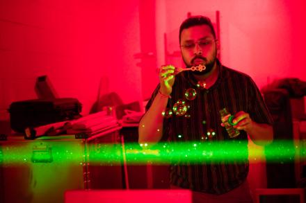Ph.D. Student Satyaki Das demonstrates the laser beam at the Lidar Research Lab during the Poker Potluck Pig Roast on Aug. 23, 2024. Photo by Bryan Whitten