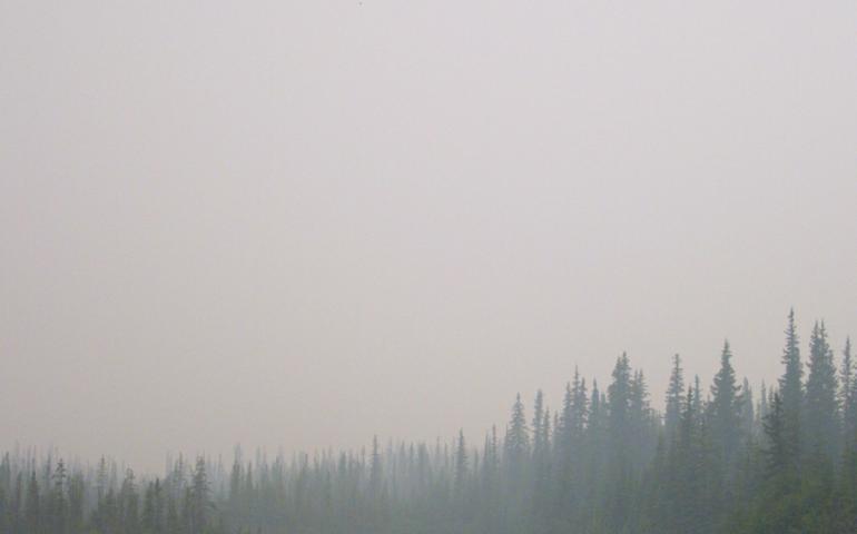 Fire smoke obscures the view of a canoeist and the sun in July 2004. Photo by Ned Rozell.