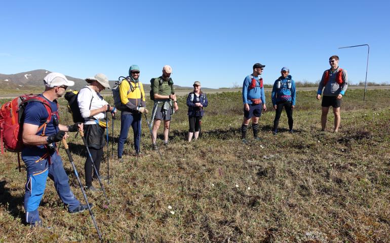 Competitors in the AlaskAcross 2024 race prepare to depart from Eagle Summit at 10 a.m. on June 8, 2024. From left are Bruno Grunau, Mark Ross, Forest Wagner, Mike Fisher, Sarah Hurkett, Clinton Brown, Tracie Curry and Curtis Henry. Photo by Ned Rozell.