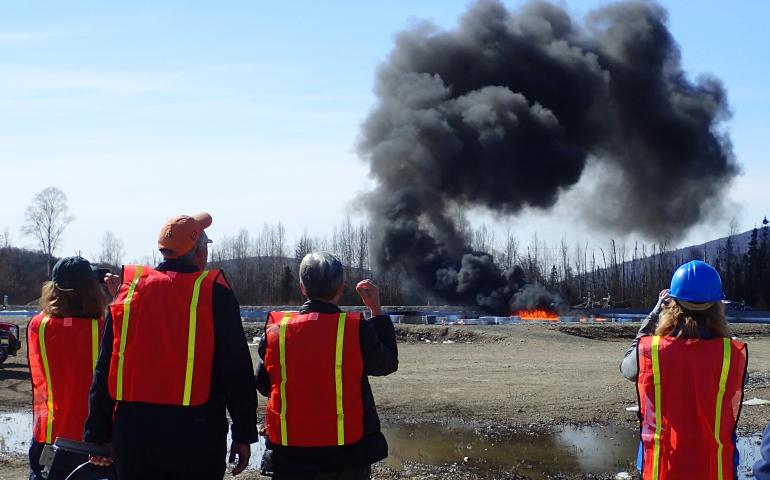 A group of researchers watch an experimental burn of crude oil in a manmade basin at Poker Flat Research Range in April 2015. Photo by Ned Rozell. 