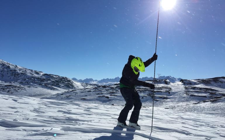 A snowmachiner in Thompson Pass measures snow depth with an avalanche probe. Photo by Gabe Wolken.