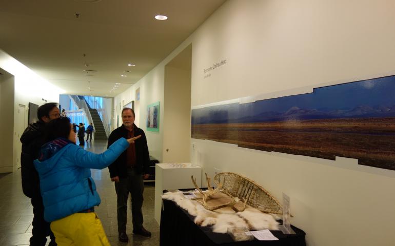 John Wright stands next to his 1979 panoramic photo of the Porcupine caribou herd in the University of Alaska Museum of the North. Photo by Ned Rozell.