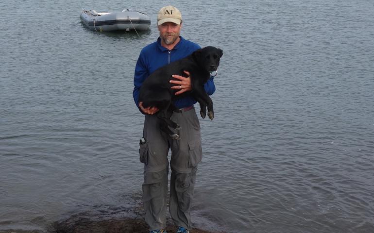 Ned Rozell and his dog Cora with the Arctic Ocean and Prudhoe Bay in the background on the day they finished their trans-Alaska hike. Photo by Becky Baird.