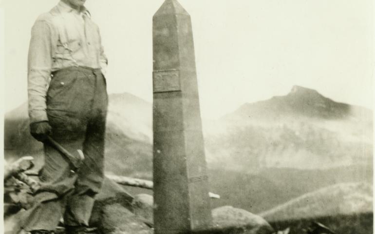 A man working with the International Boundary Commission in the early 1900s poses next to one of more than 200 obelisks that line the Alaska/Canada border. NOAA Photo Library.