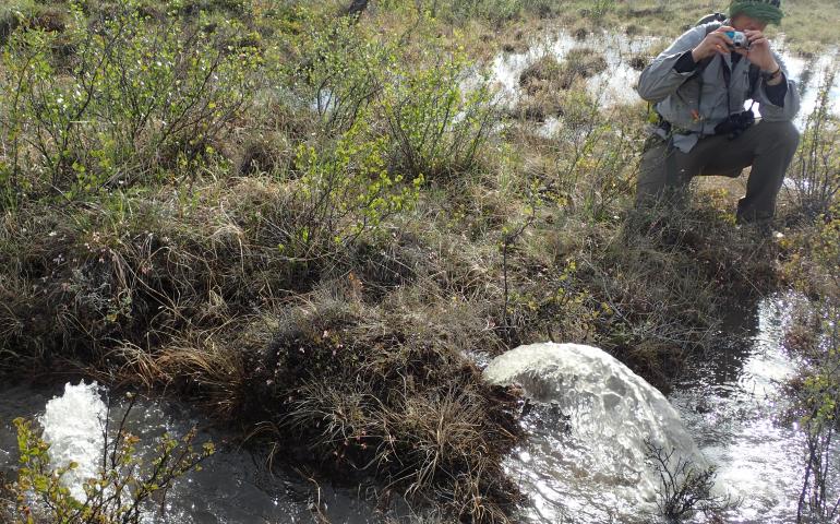 Wilderness guide Garrett Jones takes a photo of water fountaining from the tundra near the middle fork of the Chandalar River.  Photo by Ned Rozell.