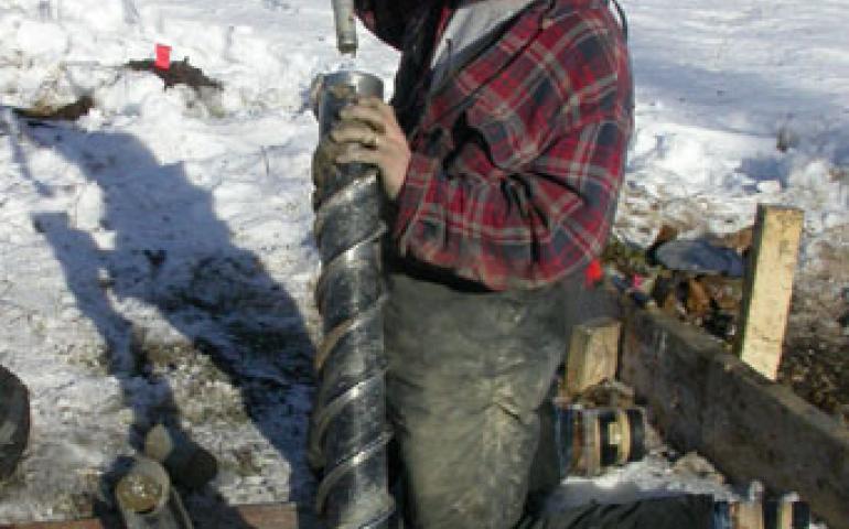  UAF research technician Jamie Hollingsworth pushes a core of frozen soil from a hollow drill bit in the Tanana Flats south of Fairbanks. Researchers are studying the area to find out how bogs affect the global carbon budget. 