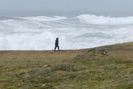 Filmmaker Fritz Mueller walks at the edge of St. Paul Island as waves crash ashore, driven by the remnants of Typhoon Merbok as it passes over St. Paul Island. Photo by Chris Maio