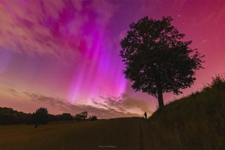 A red and rayed aurora was captured in a single 6-second exposure from Racibórz, Poland, May 10, 2024. The photographer's friend, seeing an aurora for the first time, is visible in the distance also taking images of the beautifully colorful nighttime sky. Photo by Mariusz Durlej via NASA APOD
