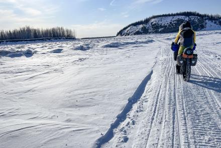 Forest Wagner rides his fat bike near Bishop Rock, right, a pinch point on the flow of the Yukon River, on April 5, 2026. Photo by Ned Rozell.