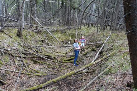 Leanne Bulger stands holding her daughter Violet, 2, next to Rose, 6, within a sunken thawed-permafrost feature called a thermokarst in the boreal forest on the University of Alaska Fairbanks campus on May 22, 2024. Photo by Ned Rozell.