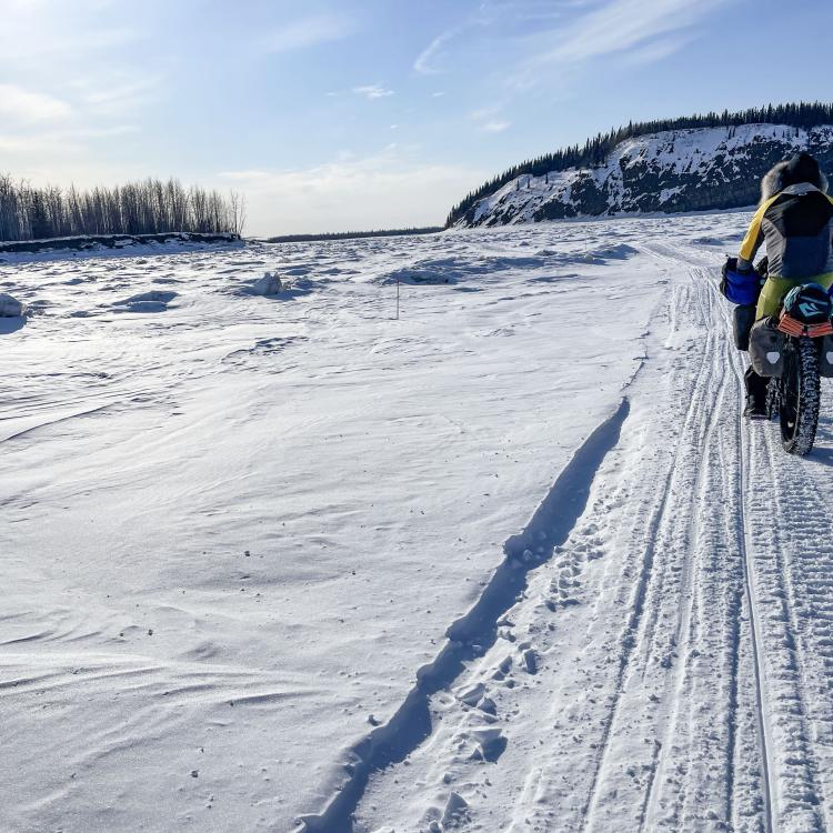Forest Wagner rides his fat bike near Bishop Rock, right, a pinch point on the flow of the Yukon River, on April 5, 2026. Photo by Ned Rozell.