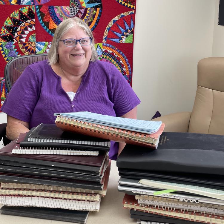 In June 2025, Kathe Rich sits in her office at Poker Flat Research Range behind notebooks she has filled with details of her 35 years at the rocket-launching facility. Photo by Ned Rozell.
