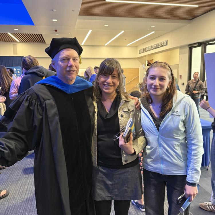 Ned, Kristen and Anna Rozell stand together in the UAF Great Hall's building lobby. Ned is dressed in UAF regalia after being awarded the AF Gold Ceremony on May 1, where Ned was awarded Science Writer Emeritus.