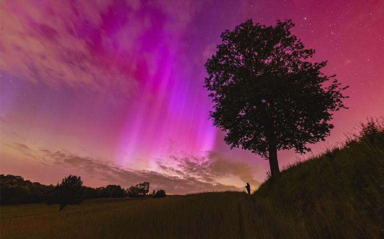A red and rayed aurora was captured in a single 6-second exposure from Racibórz, Poland, May 10, 2024. The photographer's friend, seeing an aurora for the first time, is visible in the distance also taking images of the beautifully colorful nighttime sky. Photo by Mariusz Durlej via NASA APOD